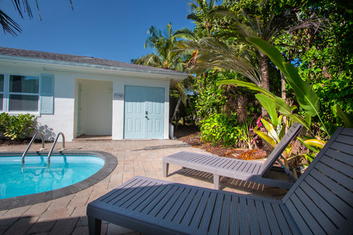 Resort-style private pool at Sea Glass Beach Compound featuring tropical palm trees, luxury Clearwater Beach rental accommodations, outdoor lounge seating, and relaxing Gulf Coast vacation rental amenities