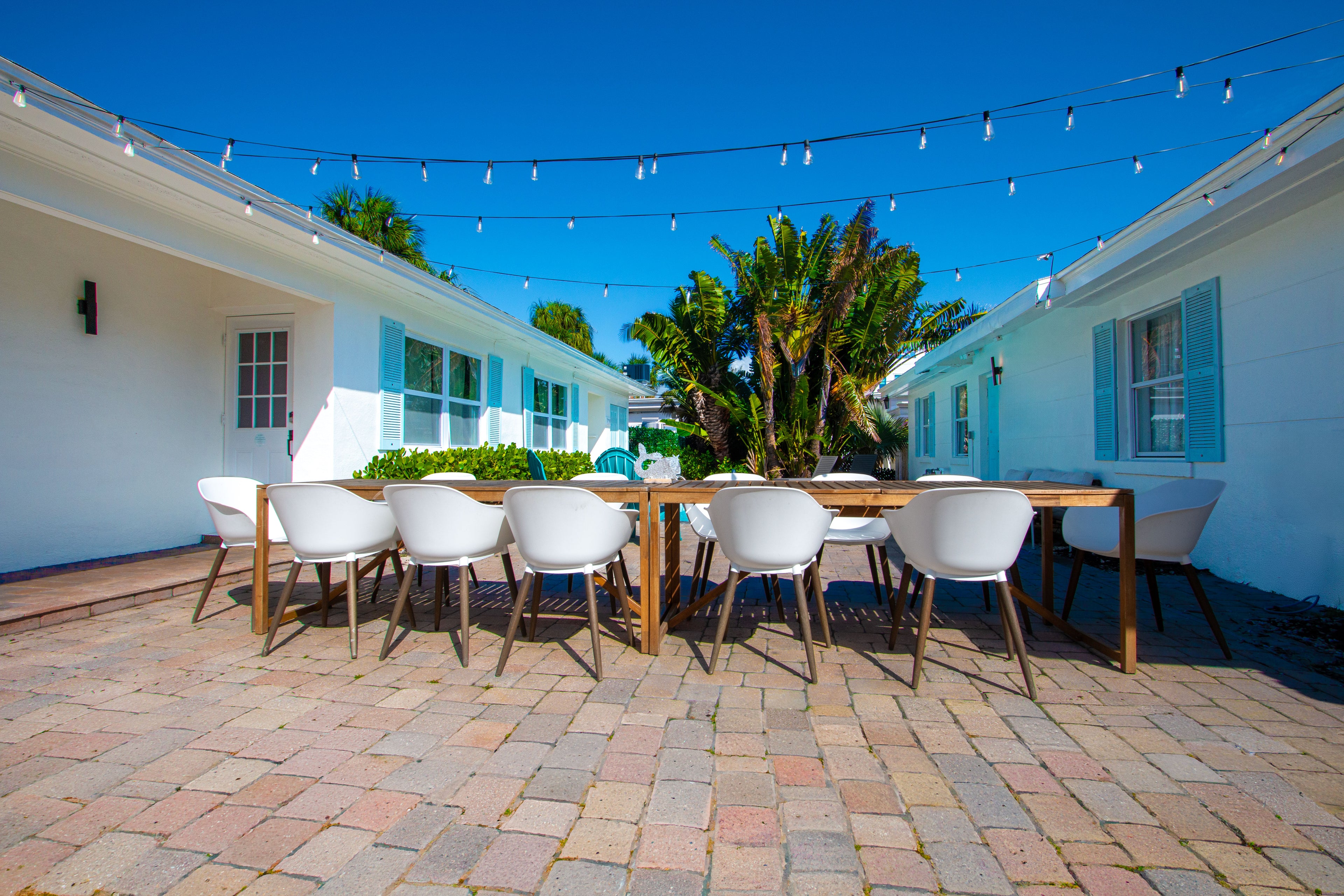 Private outdoor dining patio at Sea Glass Beach Compound featuring string lights, spacious group seating, tropical landscaping, and luxury Clearwater Beach vacation rental accommodations near the beach