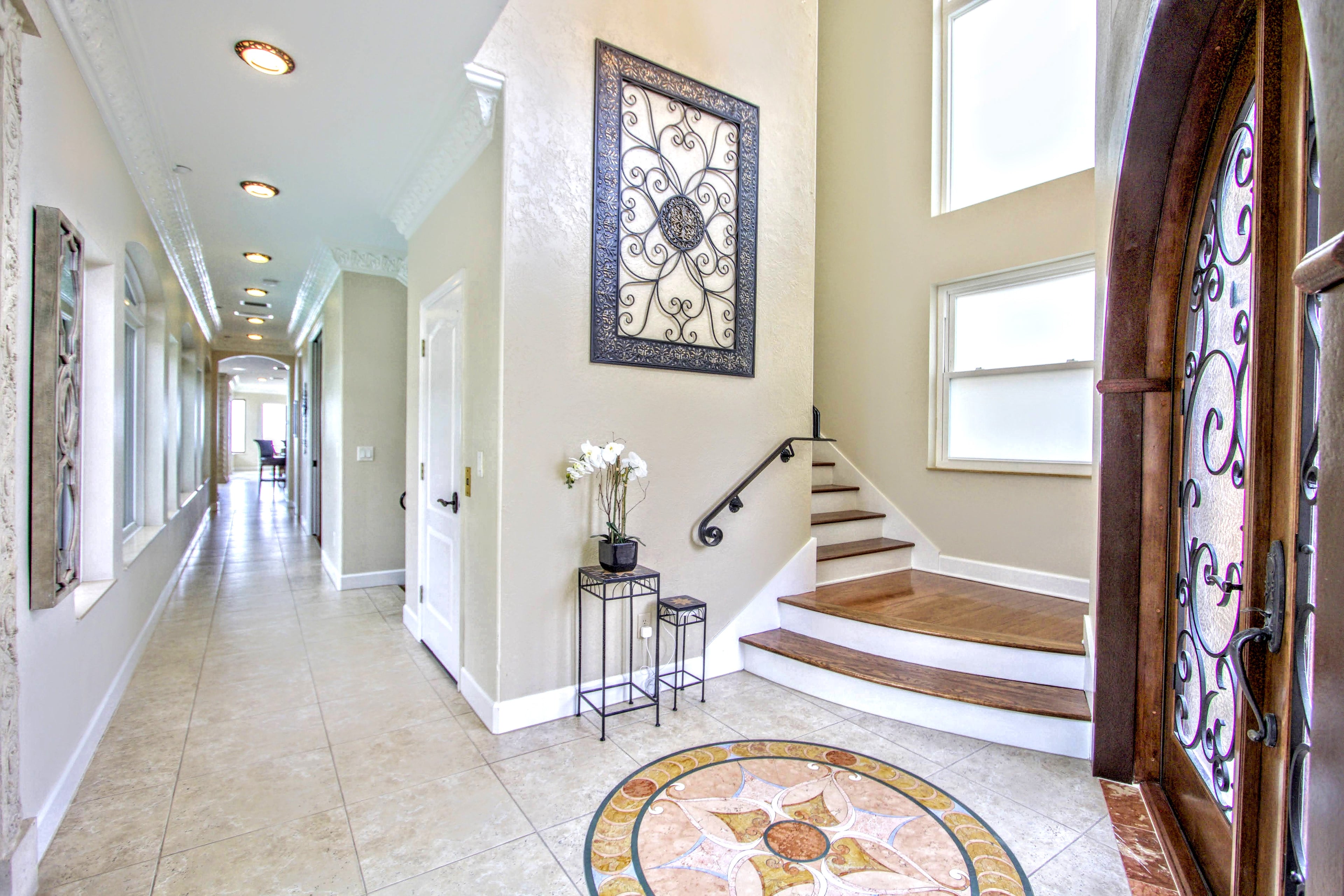 Grand Mediterranean-style entryway at Vista Del Mar Villa featuring elegant staircase, coastal luxury décor, soaring ceilings, and upscale Clearwater Beach vacation rental accommodations